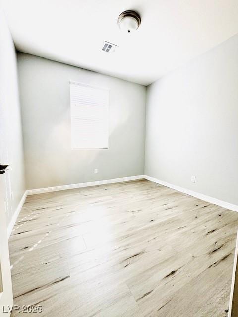 empty room with wood finished floors, visible vents, and baseboards