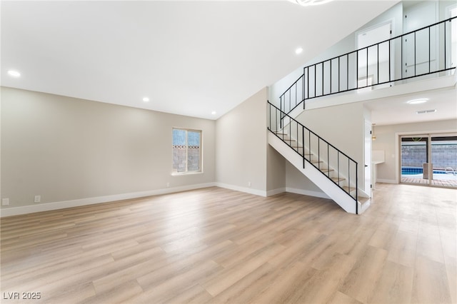 unfurnished living room featuring light wood-style flooring, stairs, baseboards, and recessed lighting