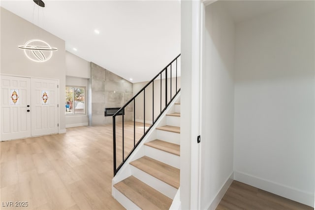 entrance foyer with recessed lighting, wood finished floors, high vaulted ceiling, baseboards, and stairs