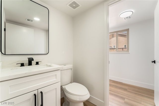 bathroom featuring visible vents, vanity, baseboards, and wood finished floors