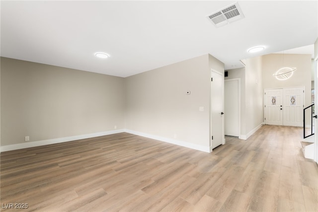 unfurnished living room with baseboards, stairway, visible vents, and light wood-style floors