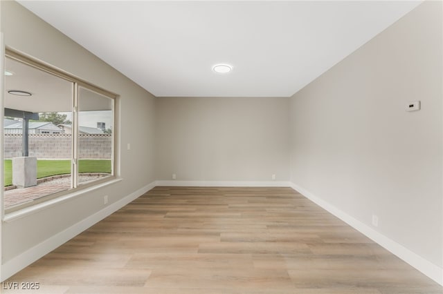 spare room featuring light wood-style floors and baseboards