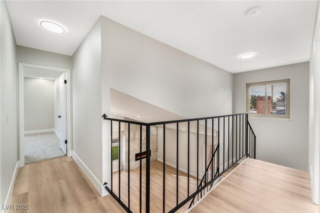 hall featuring baseboards, an upstairs landing, and wood finished floors