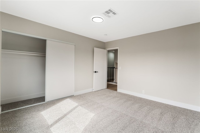 unfurnished bedroom featuring carpet floors, a closet, visible vents, and baseboards