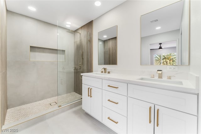 full bathroom with visible vents, a sink, a shower stall, and double vanity