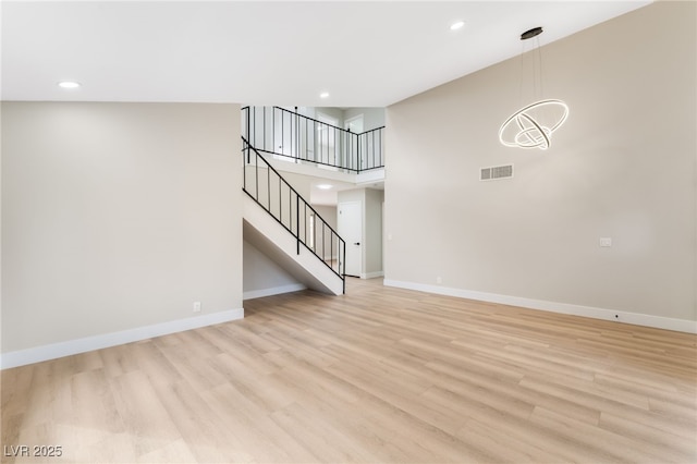 unfurnished living room featuring light wood-style flooring, recessed lighting, visible vents, baseboards, and stairs