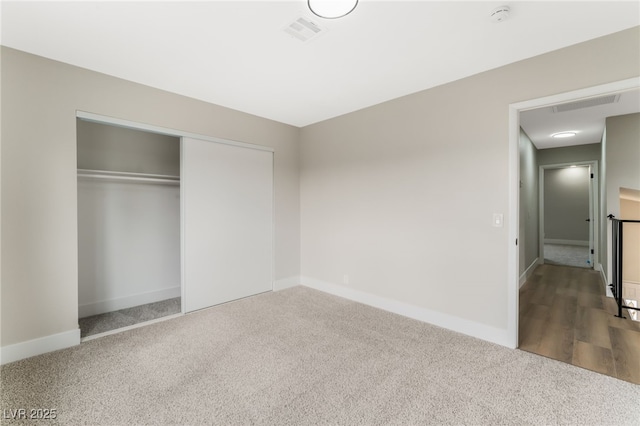 unfurnished bedroom with carpet floors, a closet, visible vents, and baseboards