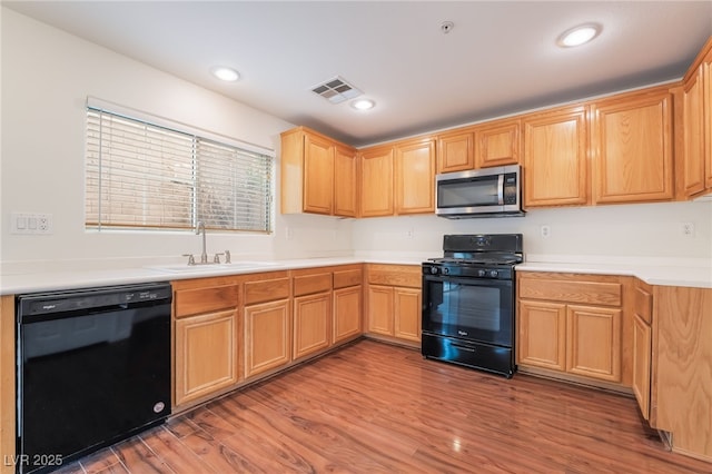 kitchen featuring recessed lighting, wood finished floors, a sink, visible vents, and black appliances