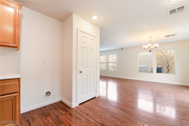 interior space featuring baseboards, visible vents, a chandelier, and wood finished floors