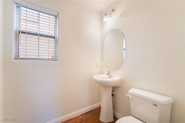 half bath featuring toilet, baseboards, and wood finished floors