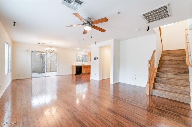 unfurnished living room with stairway, light wood-style flooring, visible vents, and ceiling fan with notable chandelier