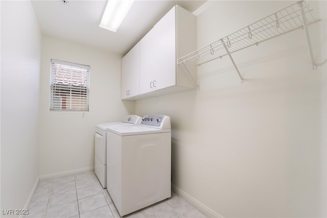 clothes washing area featuring light tile patterned floors, washer and clothes dryer, cabinet space, and baseboards