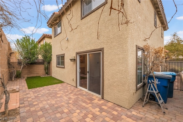 rear view of property featuring a tile roof, a fenced backyard, a patio, and stucco siding