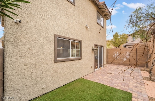 exterior space featuring a patio, fence, and stucco siding