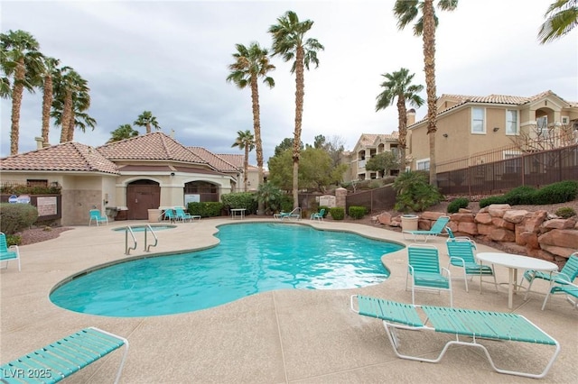 community pool with a patio area and fence