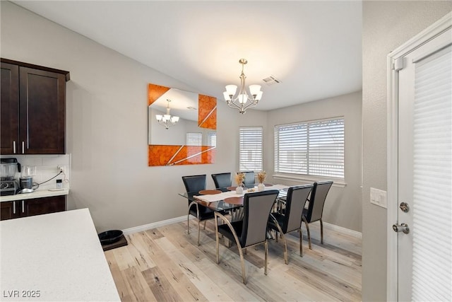 dining area with a chandelier, visible vents, light wood-type flooring, and baseboards