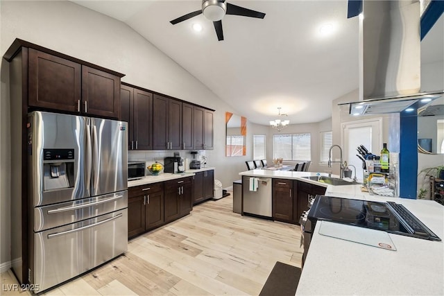 kitchen with a sink, island exhaust hood, stainless steel appliances, light countertops, and lofted ceiling