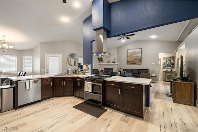 kitchen with stainless steel appliances, a peninsula, a stone fireplace, and open floor plan