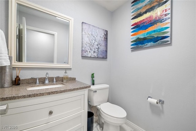 half bath featuring toilet, vanity, and baseboards