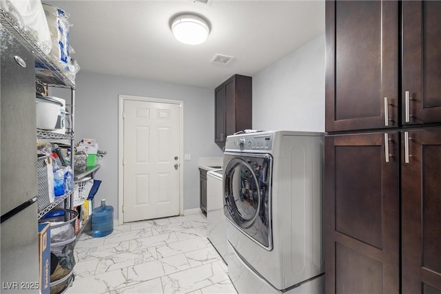 clothes washing area featuring visible vents, washer / clothes dryer, marble finish floor, and cabinet space