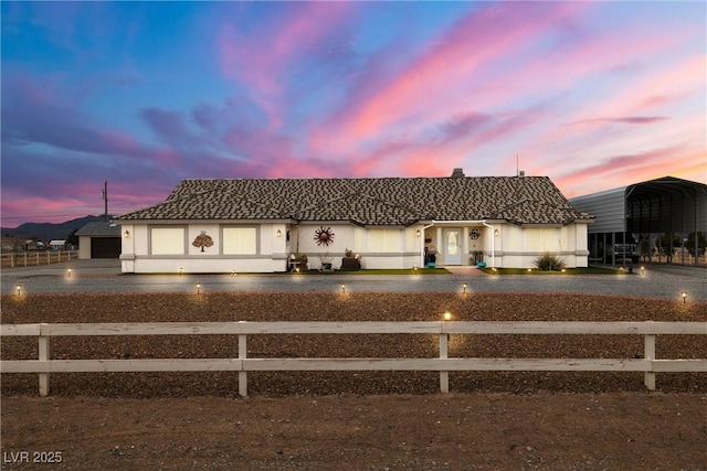 view of front facade featuring aphalt driveway, a tile roof, a fenced front yard, and a carport