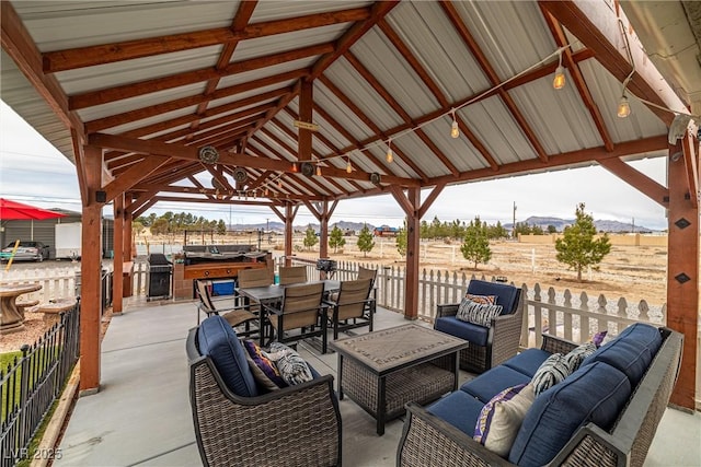 view of patio featuring outdoor dining space, fence, a gazebo, a mountain view, and an outdoor hangout area