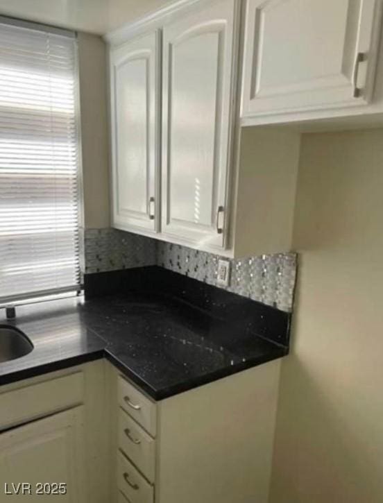kitchen featuring dark countertops and white cabinetry