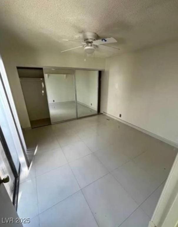 unfurnished bedroom featuring a textured ceiling, tile patterned flooring, and baseboards