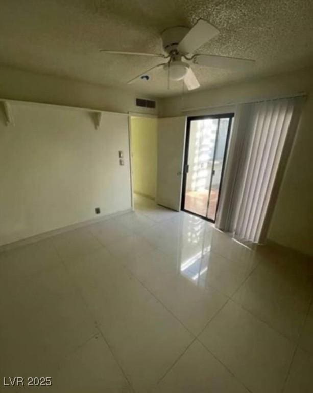 spare room with visible vents, ceiling fan, a textured ceiling, and baseboards