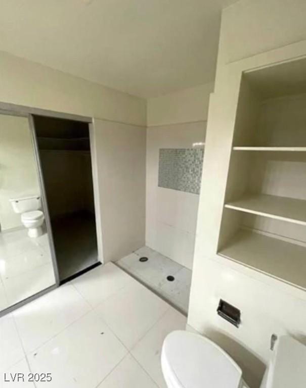 full bath with tile patterned flooring, a tile shower, and toilet