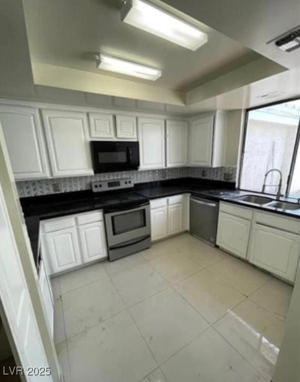 kitchen featuring a raised ceiling, stainless steel appliances, tasteful backsplash, and a sink