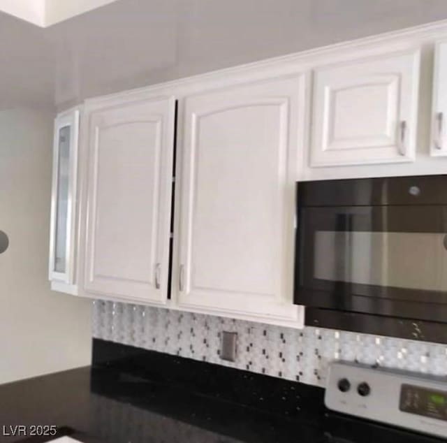 details with dark countertops, black microwave, and white cabinetry