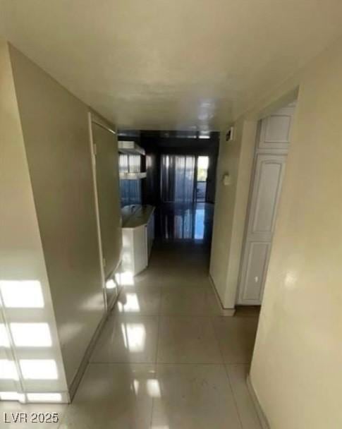 hall featuring light tile patterned flooring and baseboards