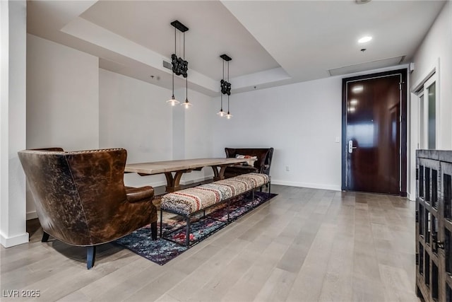 living area featuring wood finished floors, recessed lighting, a raised ceiling, and baseboards