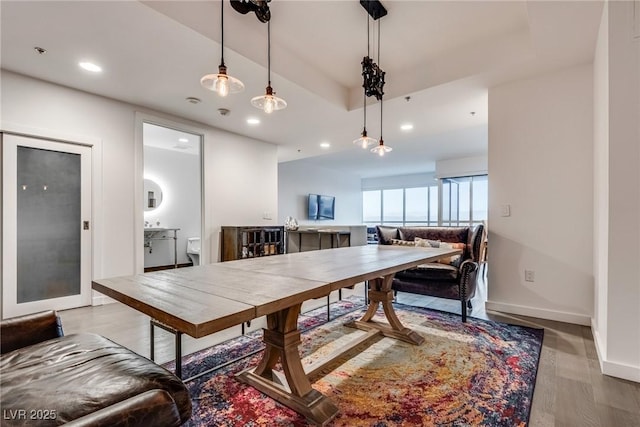 dining room with baseboards, a tray ceiling, wood finished floors, and recessed lighting