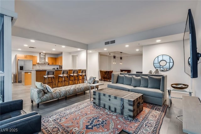 living room with light wood-style floors, visible vents, and recessed lighting