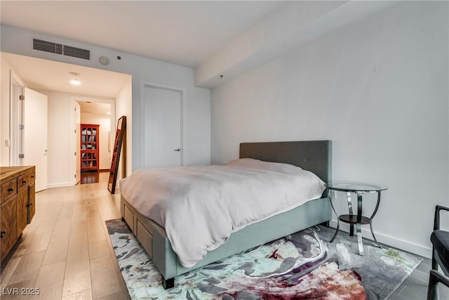 bedroom featuring baseboards, visible vents, and light wood finished floors