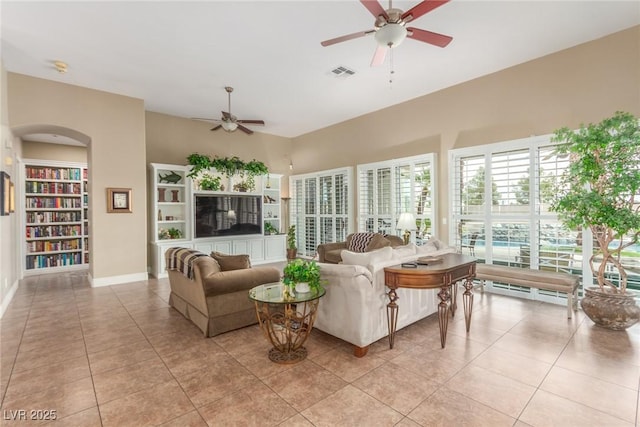 living area featuring built in features, light tile patterned floors, visible vents, and a ceiling fan