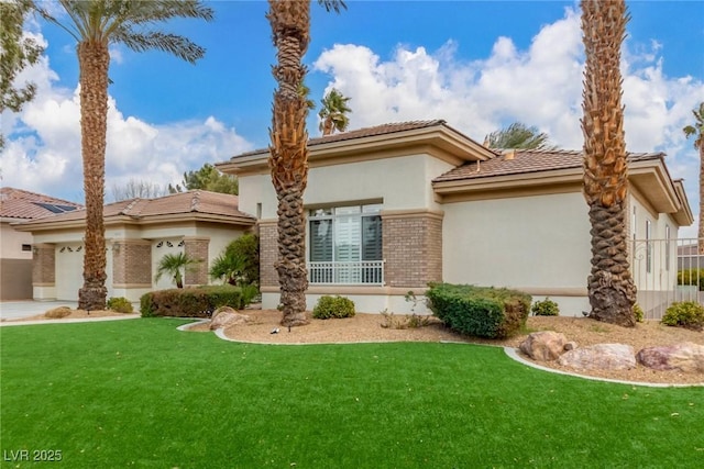 mediterranean / spanish-style home with a garage, brick siding, a tiled roof, stucco siding, and a front yard