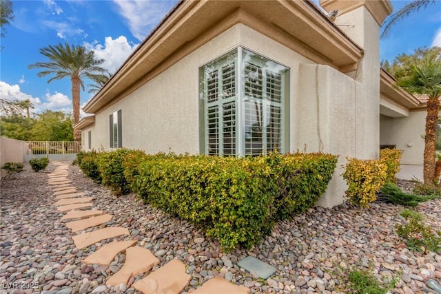 view of side of property with fence and stucco siding