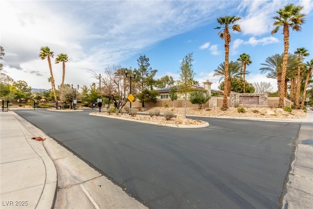 view of street with sidewalks, traffic signs, a gated entry, and curbs