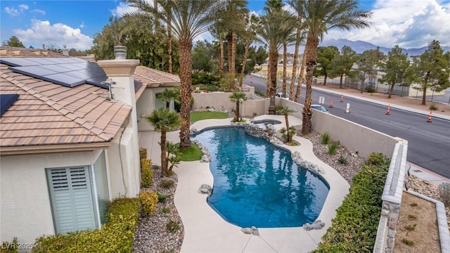 view of pool featuring a pool with connected hot tub, a patio area, a fenced backyard, and a mountain view