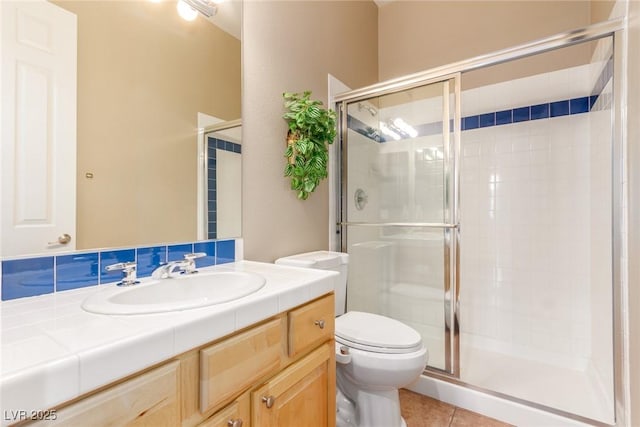 bathroom featuring toilet, a stall shower, tile patterned flooring, and vanity