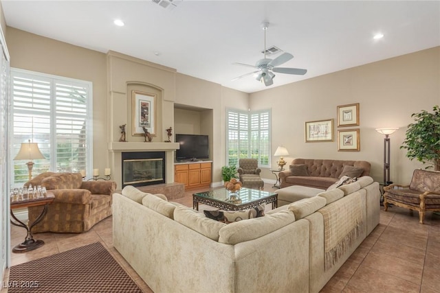 living area with light tile patterned floors, ceiling fan, recessed lighting, visible vents, and a glass covered fireplace