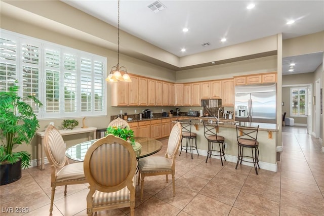 kitchen featuring a kitchen breakfast bar, light brown cabinets, visible vents, and stainless steel built in fridge