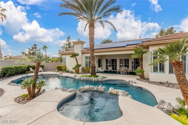 view of pool with a patio area, a pool with connected hot tub, and fence