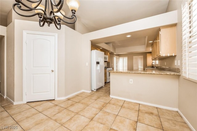 kitchen featuring a tray ceiling, an inviting chandelier, light tile patterned flooring, white appliances, and a peninsula