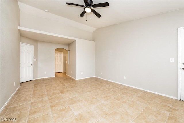 empty room with a ceiling fan, arched walkways, baseboards, and light tile patterned floors