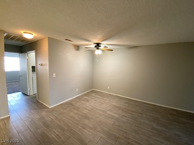 spare room with dark wood-style floors, visible vents, ceiling fan, a textured ceiling, and baseboards