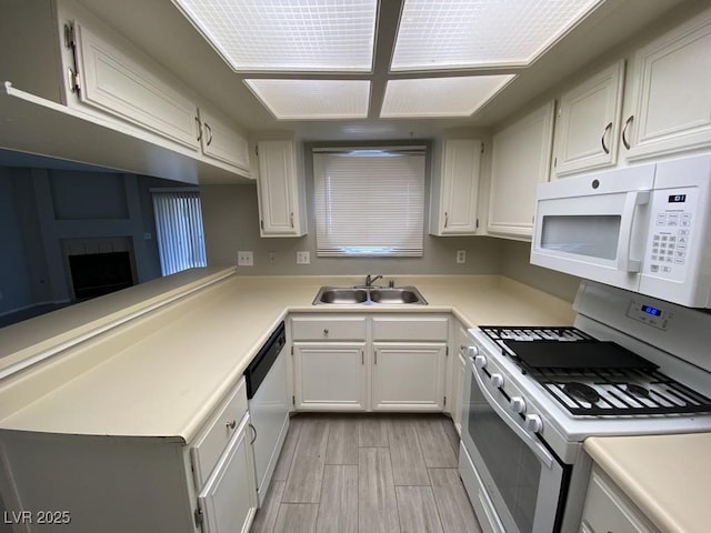 kitchen with light countertops, white appliances, wood finish floors, and a sink